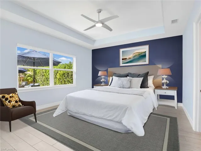 Bedroom featuring ceiling fan, light hardwood / wood-style floors, and a raised ceiling