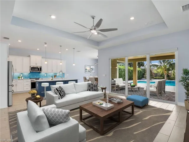 Living room featuring a raised ceiling, light hardwood / wood-style flooring, ceiling fan, and sink