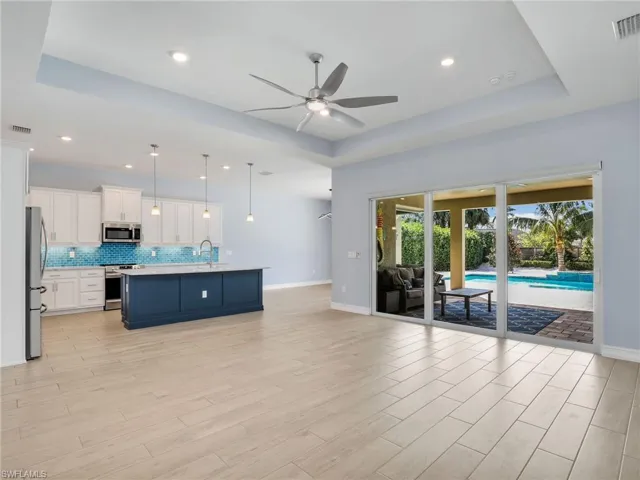 Living room featuring ceiling fan, light hardwood / wood-style floors, a raised ceiling, and sink