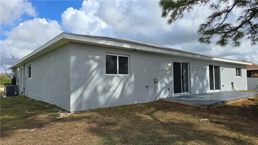 Rear view of property with stucco siding, a yard, and a patio