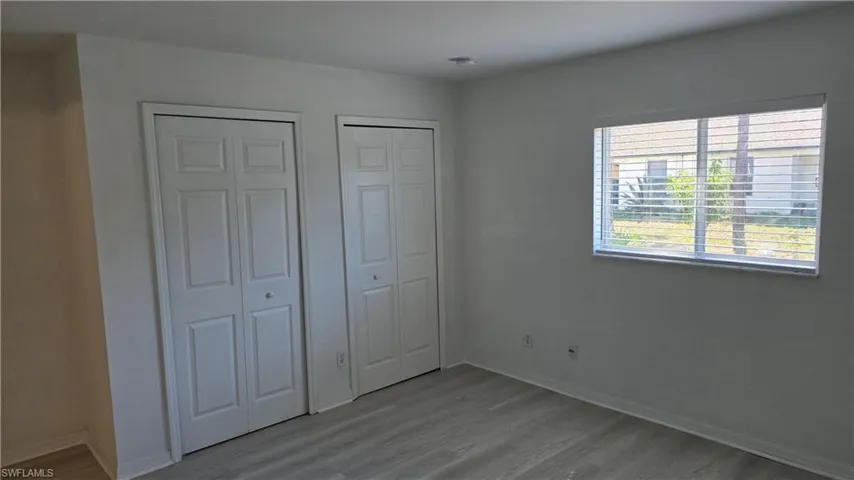 Unfurnished bedroom with light wood-style floors and two closets