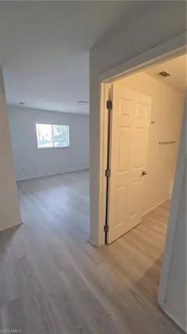 Corridor with light wood-style flooring and baseboards