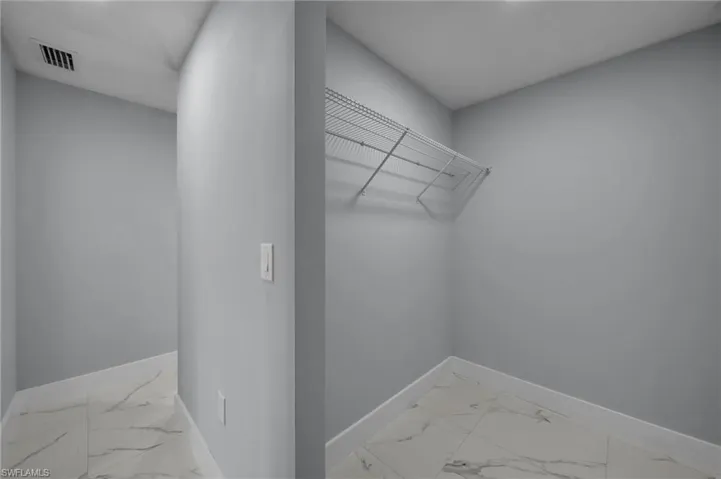 Spacious closet featuring visible vents and marble finish floor
