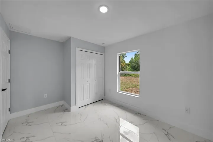 Unfurnished bedroom featuring visible vents, a closet, marble finish floor, baseboards, and attic access