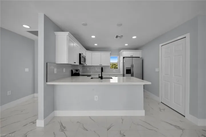 Kitchen with baseboards, a sink, marble finish floor, and stainless steel appliances