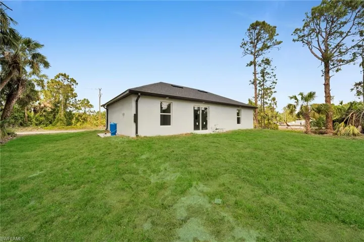 Rear view of house featuring a lawn and stucco siding