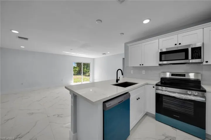 Kitchen with a sink, marble finish floor, stainless steel appliances, recessed lighting, and visible vents