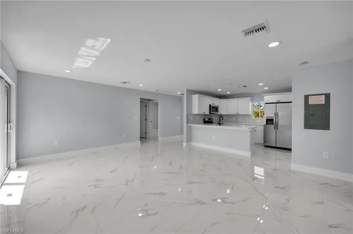 Unfurnished living room featuring visible vents, a sink, baseboards, marble finish floor, and recessed lighting