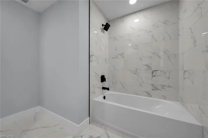 Full bath with baseboards, shower / bathtub combination, and marble finish floor
