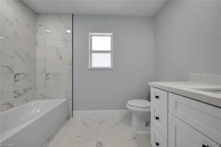 Full bath with toilet, baseboards, marble finish floor, and vanity