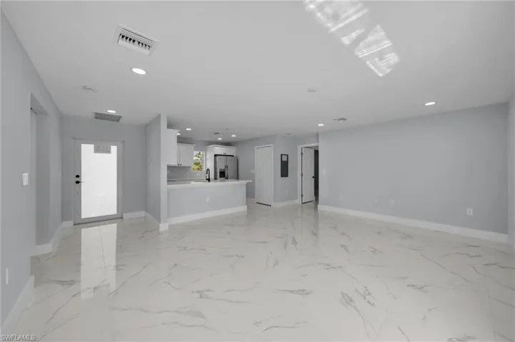 Unfurnished living room with a sink, baseboards, recessed lighting, and visible vents
