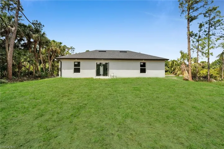 Back of house with stucco siding and a yard