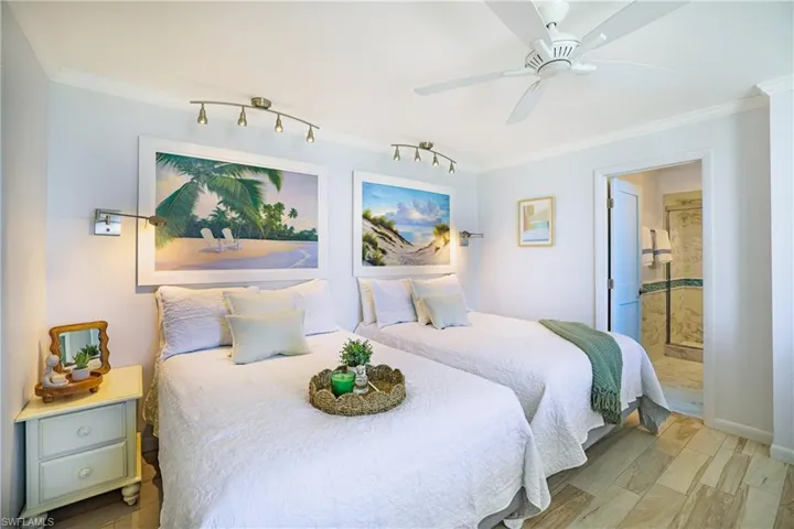 Bedroom with ensuite bathroom, ornamental molding, light wood-type flooring, and ceiling fan