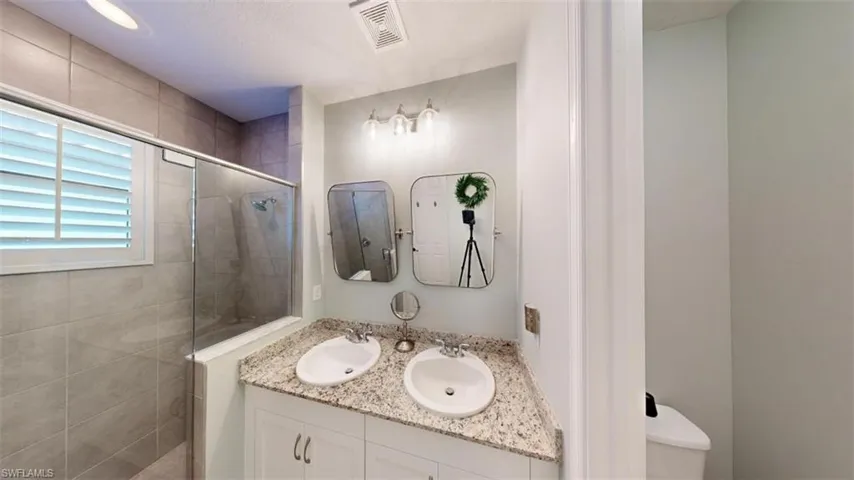 Bathroom with an enclosed shower, toilet, and vanity