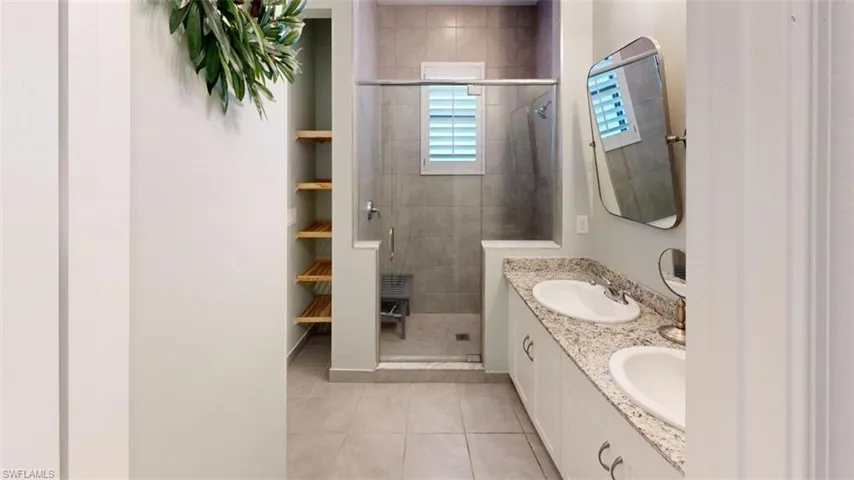 Bathroom with a shower with shower door, dual vanity, and tile flooring