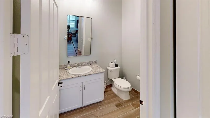Bathroom with hardwood / wood-style floors, vanity, and toilet