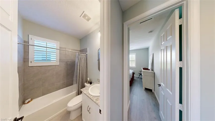 Full bathroom featuring shower / bath combination with curtain, a textured ceiling, hardwood / wood-style flooring, toilet, and vanity