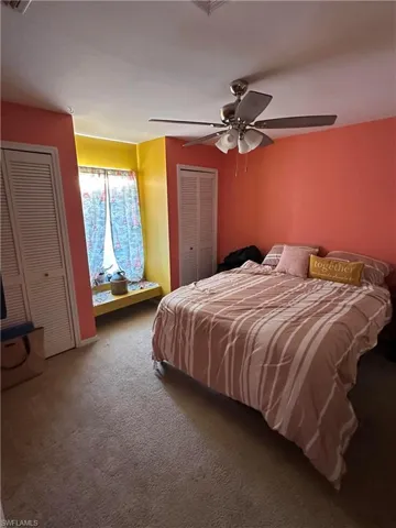 Bedroom with multiple closets, carpet floors, and ceiling fan