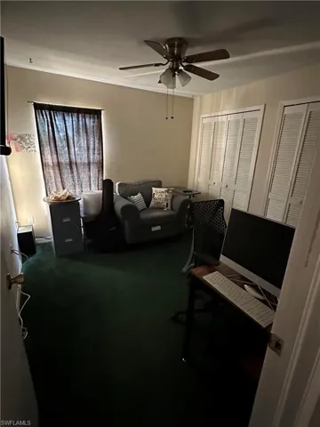 Office area with dark colored carpet and a ceiling fan
