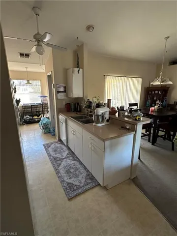Kitchen featuring decorative light fixtures, white cabinetry, a peninsula, and light countertops