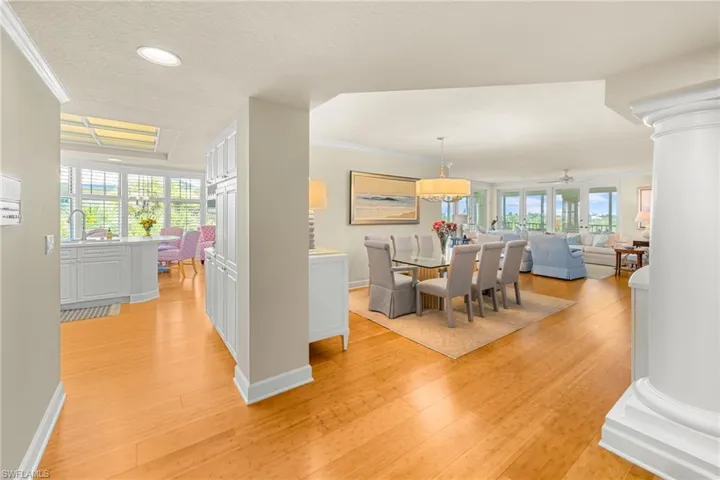 Dining space with ornamental molding, ornate columns, light wood finished floors, a textured ceiling, and healthy amount of natural light