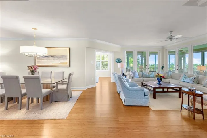 Living area with light wood-type flooring, ornamental molding, and ceiling fan