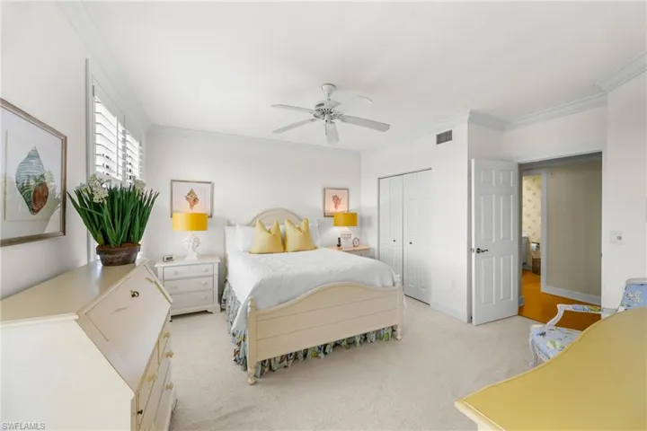 Bedroom featuring light colored carpet, crown molding, a closet, and ceiling fan