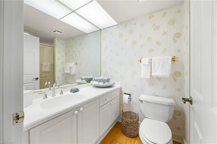 Full bath with vanity, light wood-style flooring, and a shower