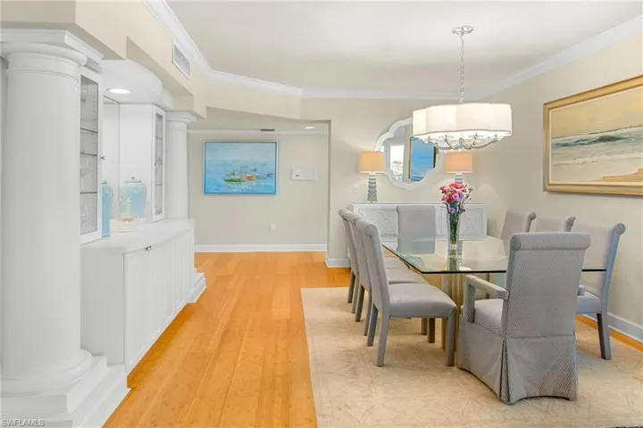 Dining room with light wood-style flooring, ornamental molding, and ornate columns