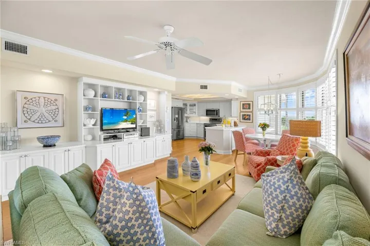 Living area with crown molding, light wood-style flooring, a ceiling fan, and hanging lights