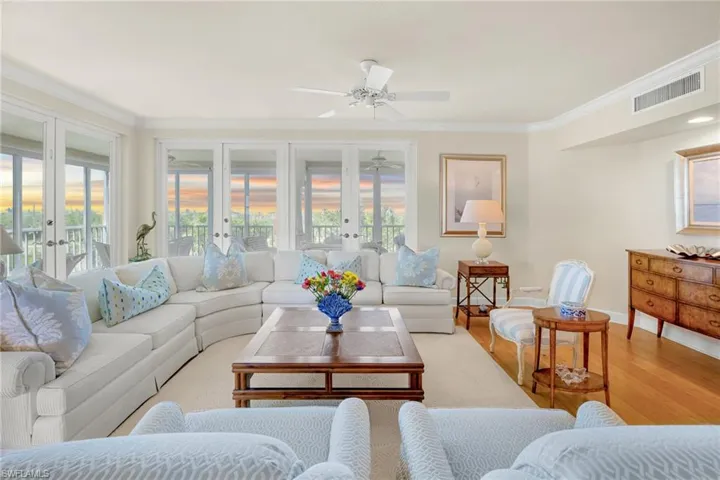 Living room with wood finished floors, crown molding, a ceiling fan, and french doors
