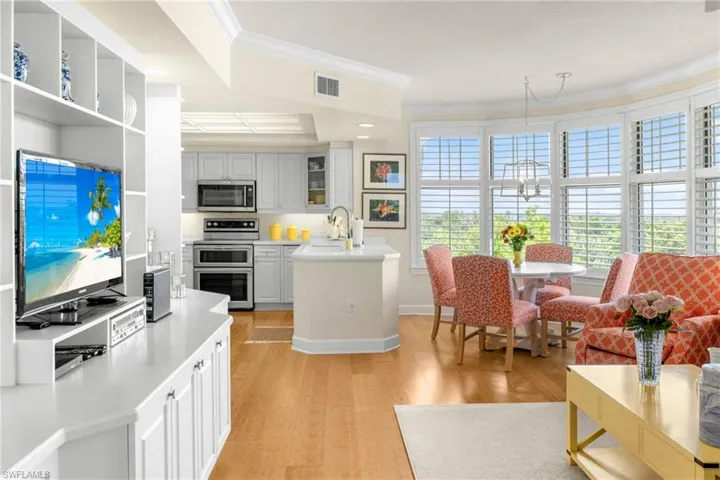 Kitchen with stainless steel appliances, light wood-style floors, crown molding, recessed lighting, and open shelves
