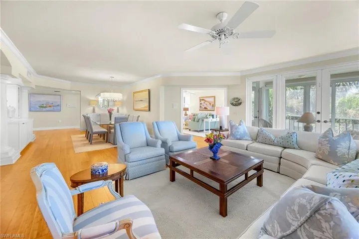 Living area with hardwood / wood-style flooring, ornamental molding, ornate columns, and ceiling fan