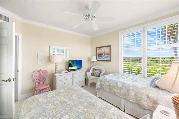 Carpeted bedroom featuring crown molding and ceiling fan