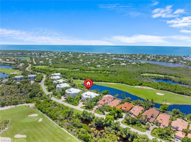 Aerial view of residential area featuring a nearby body of water and a golf course