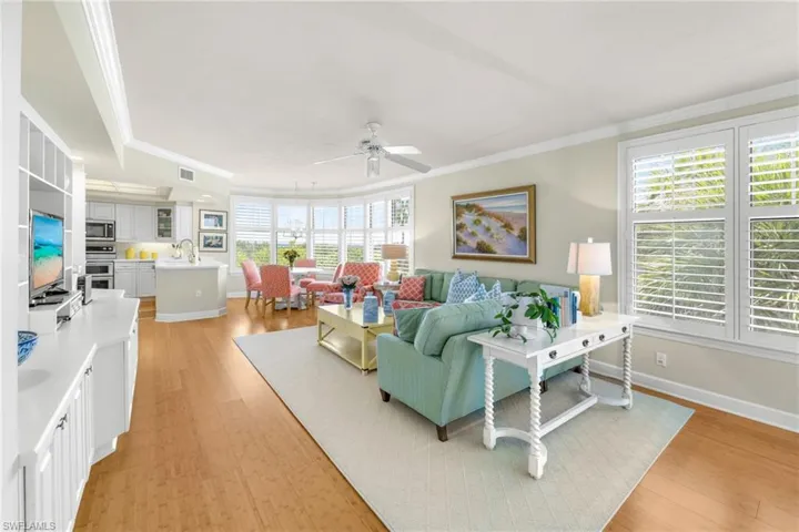 Living room with light wood-style floors, a ceiling fan, and ornamental molding