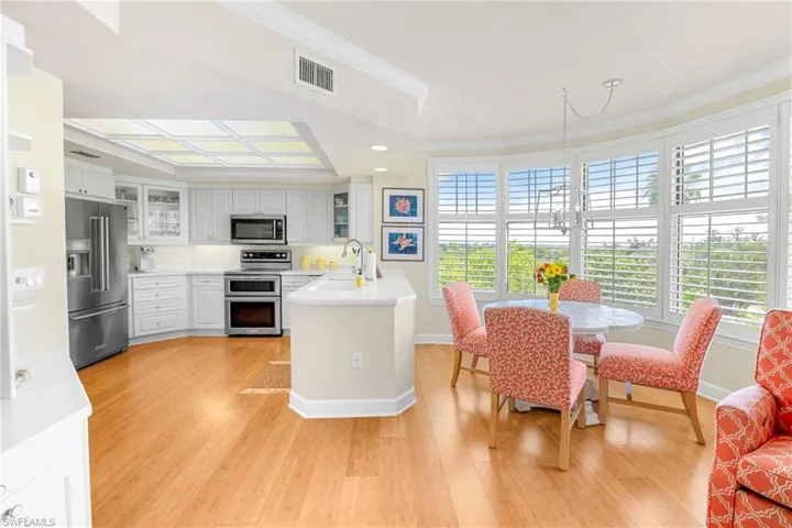Kitchen featuring light countertops, stainless steel appliances, white cabinetry, glass insert cabinets, and light wood-type flooring