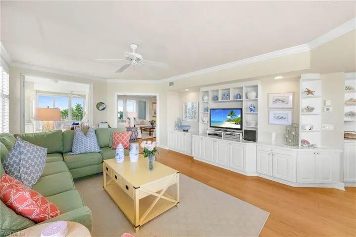 Living room featuring light wood-style floors, ornamental molding, and ceiling fan