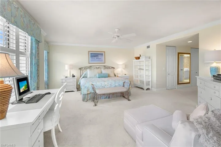 Bedroom with ornamental molding, ceiling fan, light colored carpet, and an office area