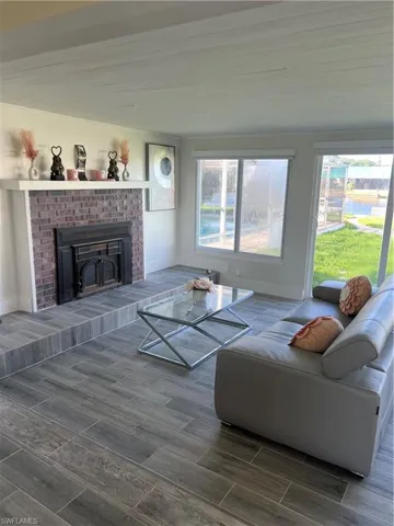 Living room with healthy amount of natural light, wood tiled floors, and a brick fireplace