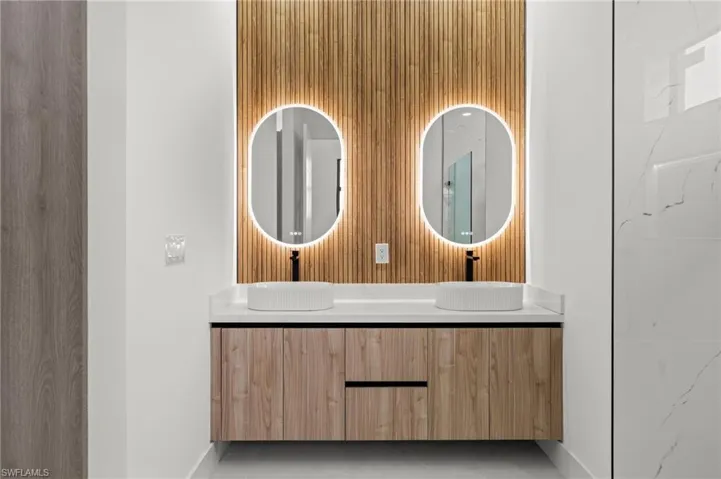 Dual vessel sinks on a floating wood-finish vanity with a light-toned countertop