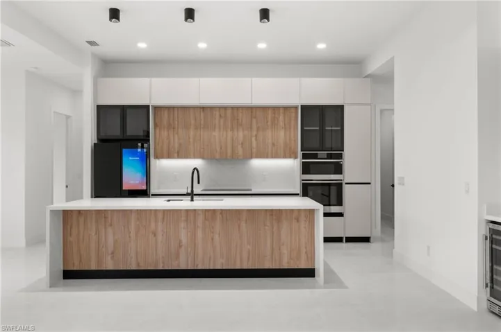 Modern kitchen featuring a large central island with wood-finish paneling and a waterfall countertop