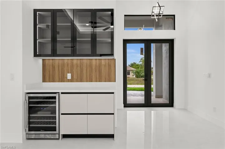 Integrated wet bar featuring a built-in wine refrigerator, white countertop, and wood-slat backsplash