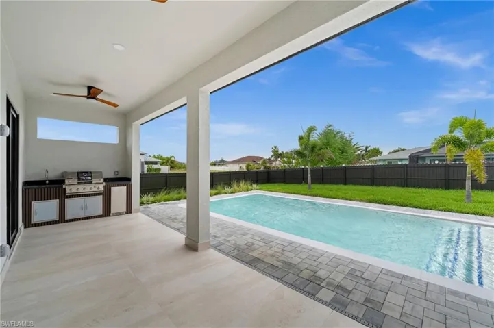 Covered patio featuring an outdoor kitchen with grill, sink, and integrated cabinetry