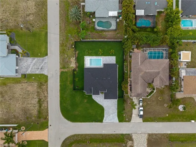 Aerial overview showcasing a contemporary residence with a dark shingle roof and an integrated swimming pool