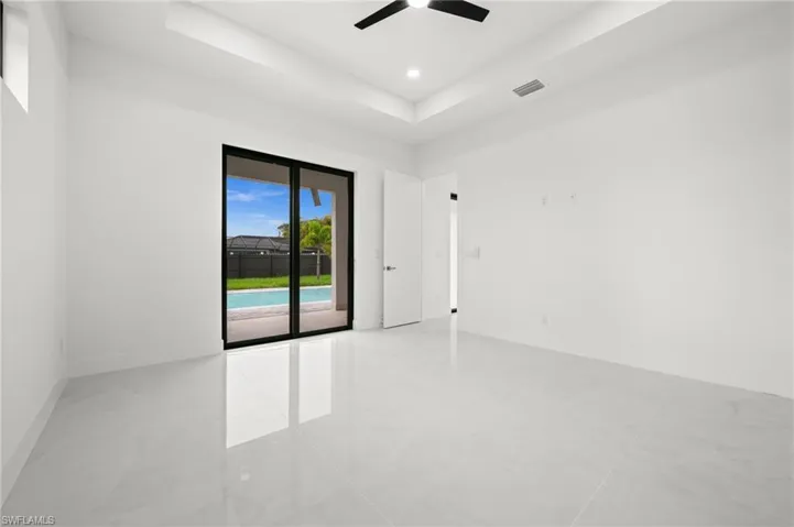 Spacious room with polished tile flooring, tray ceiling, and modern ceiling fan