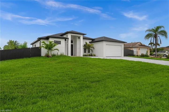 Modern stucco exterior with a dark shingle roof, integrated two-car garage, and a gravel driveway