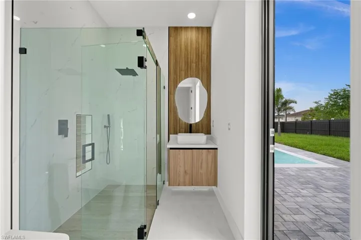 Spacious bathroom featuring a glass-enclosed shower with a rainfall showerhead, a floating vanity with a vessel sink, and a wood-finish accent wall