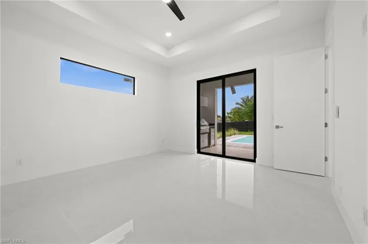 Spacious room featuring large format tile flooring, a horizontal accent window, and a tray ceiling with recessed lighting