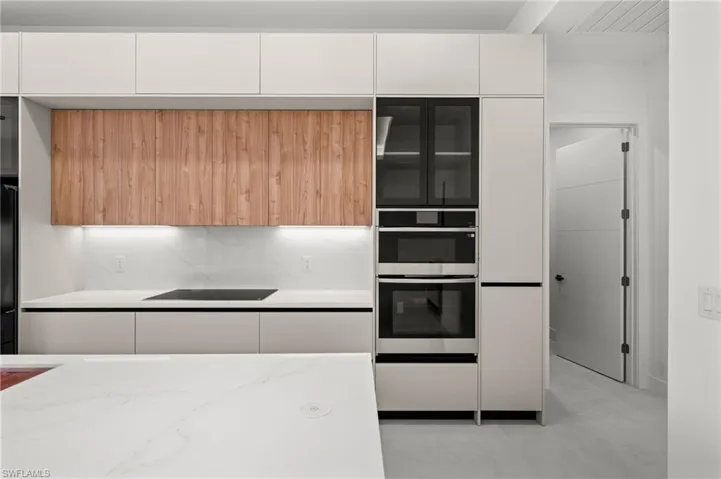 Contemporary kitchen featuring flat-panel cabinetry, integrated stainless steel appliances, a built-in oven and microwave, and a smooth cooktop